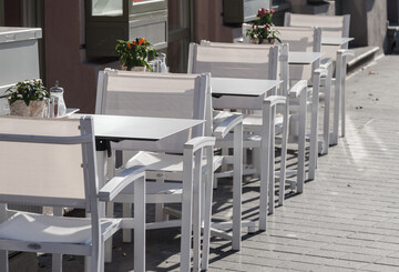 Vier weiße Tische und Stühle eines Straßencafés