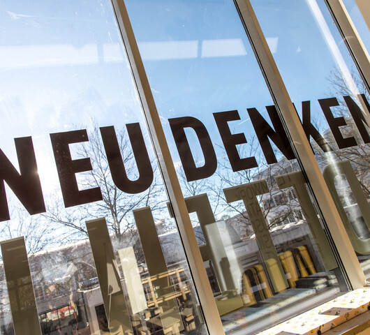 Eine gespiegelte Fensterfront zeigt den Text "Neu denken".